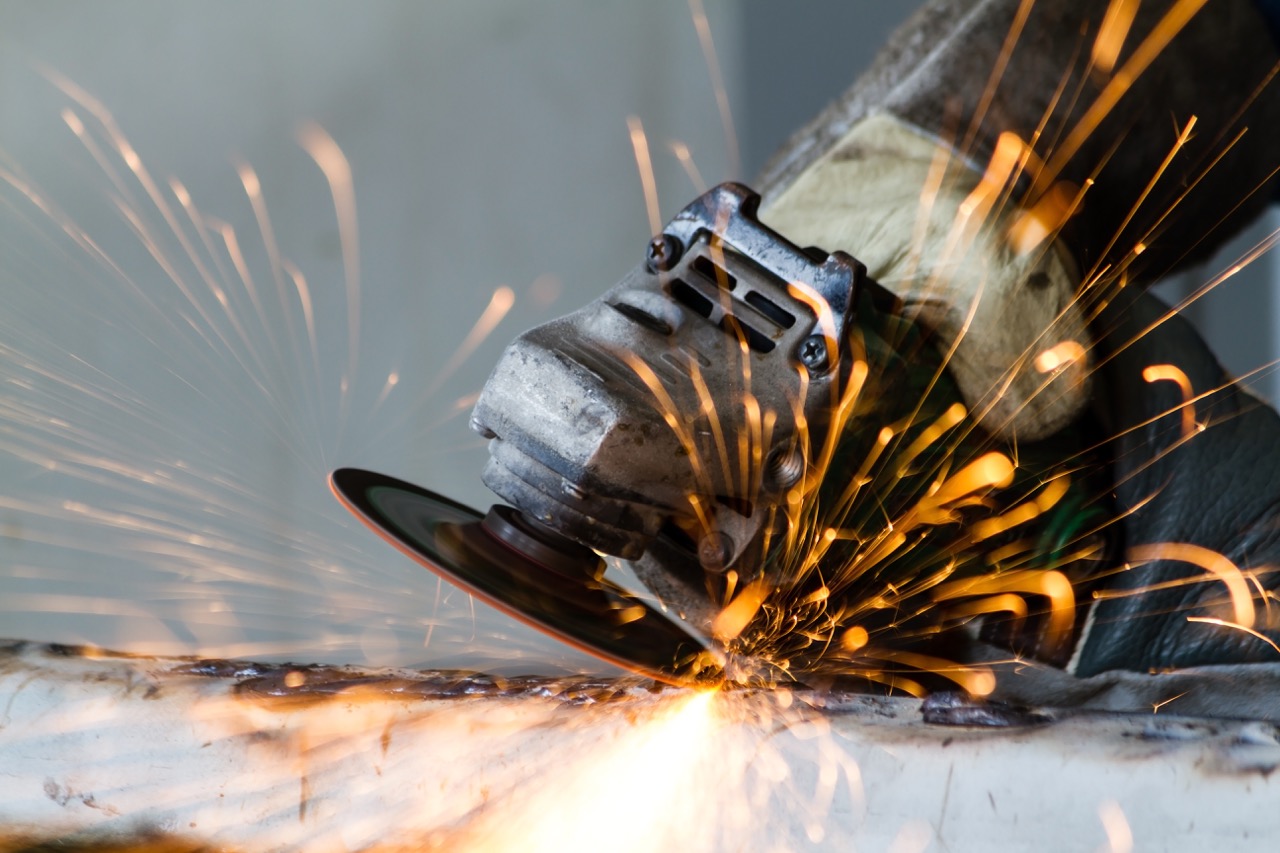 Angle grinder cutting metal — sparks flying across a steel workpiece